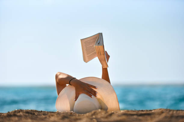 Femme qui lit un livre au bord de la plage, de dos